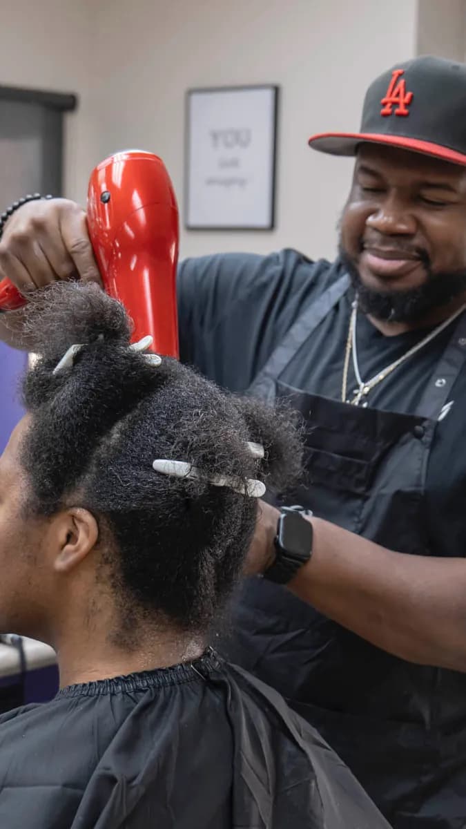 Young hairstylist cutting client hair in modern salon